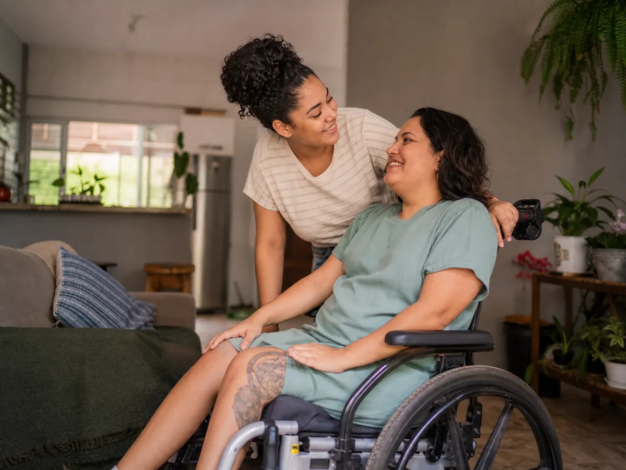 Mulher brasileira em cadeira de rodas conversando com uma familiar em casa